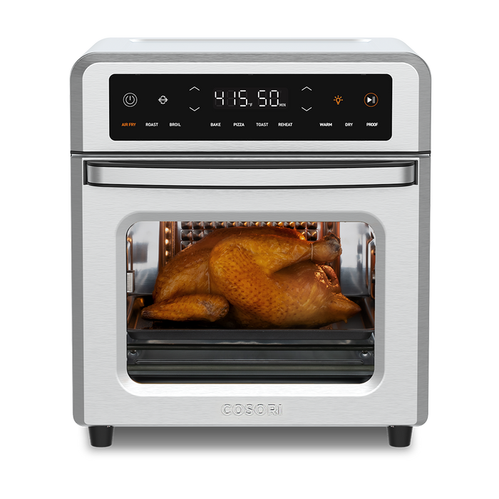 Cosori 13-Quart Air Fryer Oven with a whole roasted chicken cooking inside. Stainless steel finish