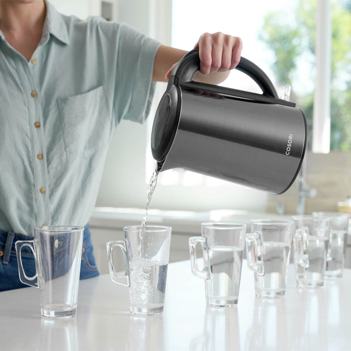 Person pouring hot water from COSORI Double-Wall Stainless Steel Electric Kettle into cups